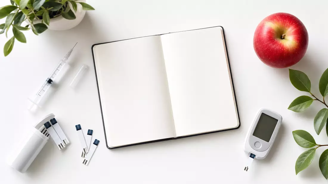 Flatlay mit Spritze, Teststreifen, Notizbuch und Apfel auf weißem Untergrund