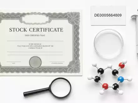 Flatlay-Arrangement mit Aktienzertifikat und ISIN-Karte DE0005664809 visualisiert die Aktie von Evotec SE als Biotech-Investment - Foto: THN
