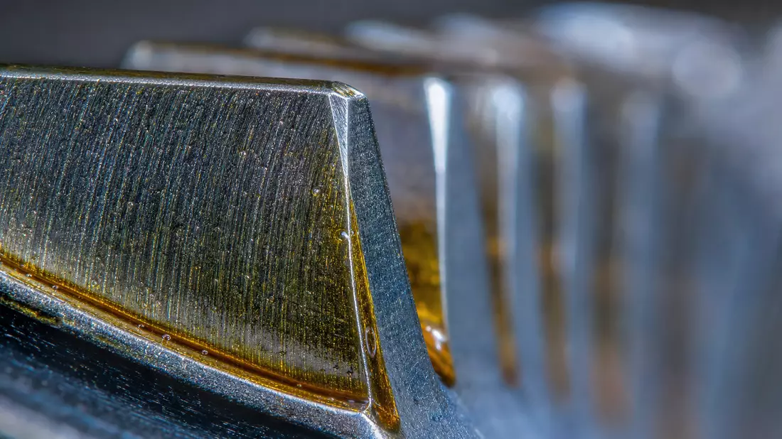Extreme Makroaufnahme gehärteter Stirnrad-Zahnflanken mit goldenem Schmierölfilm