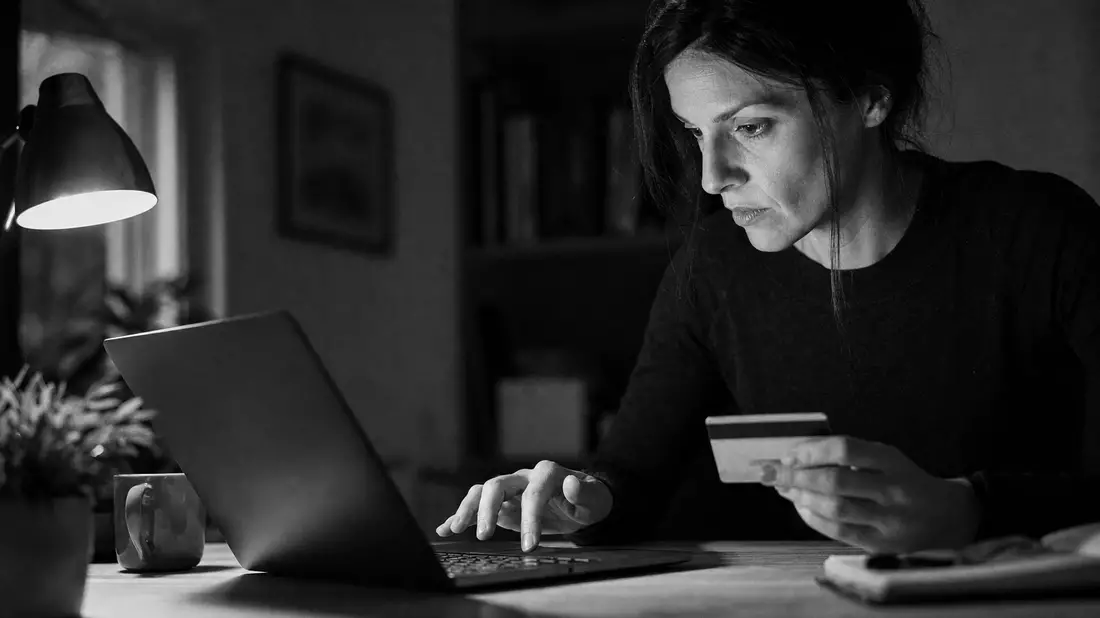 Frau tippt Kartendaten am Laptop, Schwarzweiß-Reportage