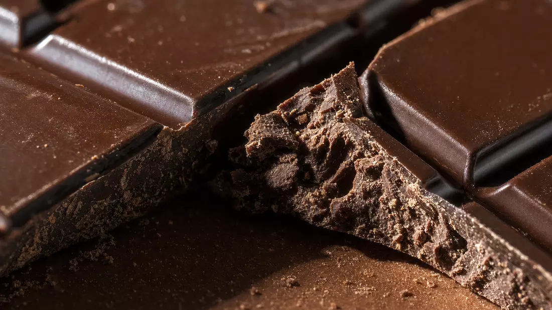 Extreme Makroaufnahme einer gebrochenen dunklen Schokoladentafel mit rauer Bruchkante