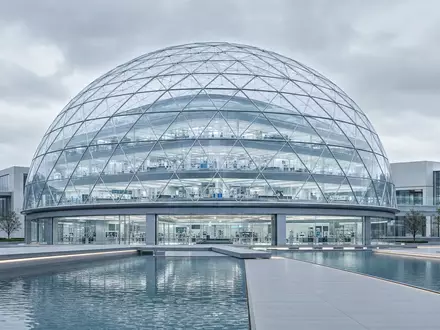 Palantir Technologies Inc (US69608A1088) – futuristische Glas-Kuppel-Forschungseinrichtung mit klaren Linien und Spiegelteich - Foto: THN