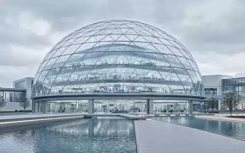 Palantir Technologies Inc (US69608A1088) – futuristische Glas-Kuppel-Forschungseinrichtung mit klaren Linien und Spiegelteich - Foto: THN