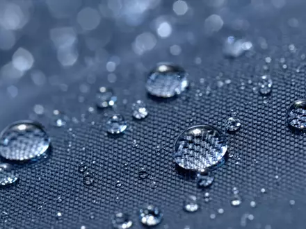 Zurich Insurance Group AG CH0011075394 – Extreme Makro-Nahaufnahme von Wassertropfen auf Regenschirm-Textilgewebe in kühlen Blautönen - Foto: THN