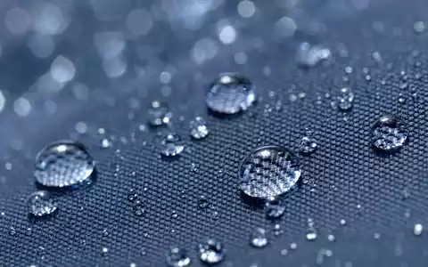 Zurich Insurance Group AG CH0011075394 – Extreme Makro-Nahaufnahme von Wassertropfen auf Regenschirm-Textilgewebe in kühlen Blautönen - Foto: THN
