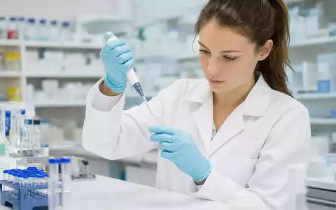 Novartis AG CH0012005267 – Forscherin pipettiert präzise in steriler Pharmalaborumgebung mit Reagenzgläsern - Foto: THN
