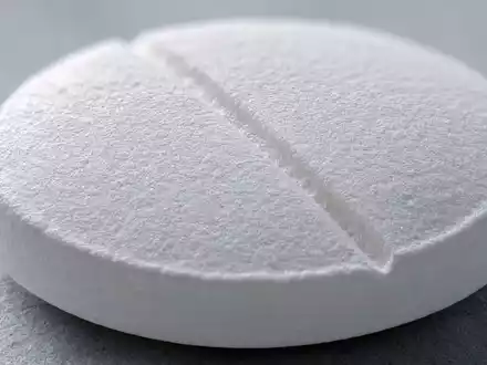 Novartis AG CH0012005267 – Extreme Makroaufnahme einer weißen Tablette mit Bruchkerbe und feiner Oberflächentextur - Foto: THN