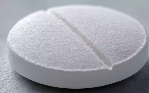 Novartis AG CH0012005267 – Extreme Makroaufnahme einer weißen Tablette mit Bruchkerbe und feiner Oberflächentextur - Foto: THN
