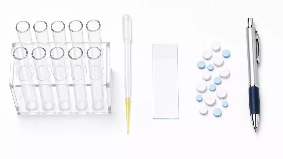 Flatlay Labor-Utensilien: Reagenzgläser, Pipette, Glasplatte, Tabletten und Stift auf Weiß