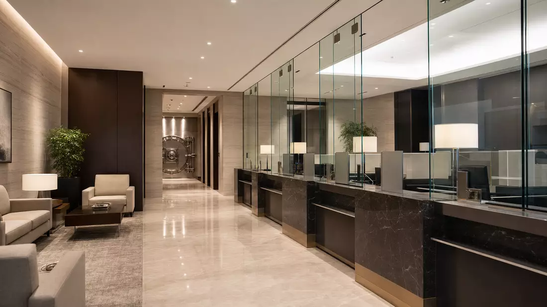 Moderner Bankschalter mit Glaspartitionen und Stahltresor im Hintergrund