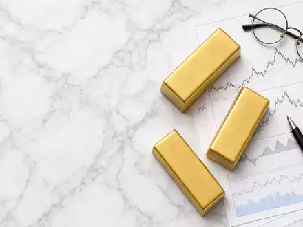 UBS Group AG CH0244767585 als Flatlay mit Goldbarren, Aktien-Charts, Brille und Stift auf weißem Marmortisch - Foto: THN