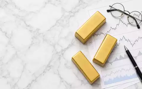 UBS Group AG CH0244767585 als Flatlay mit Goldbarren, Aktien-Charts, Brille und Stift auf weißem Marmortisch - Foto: THN