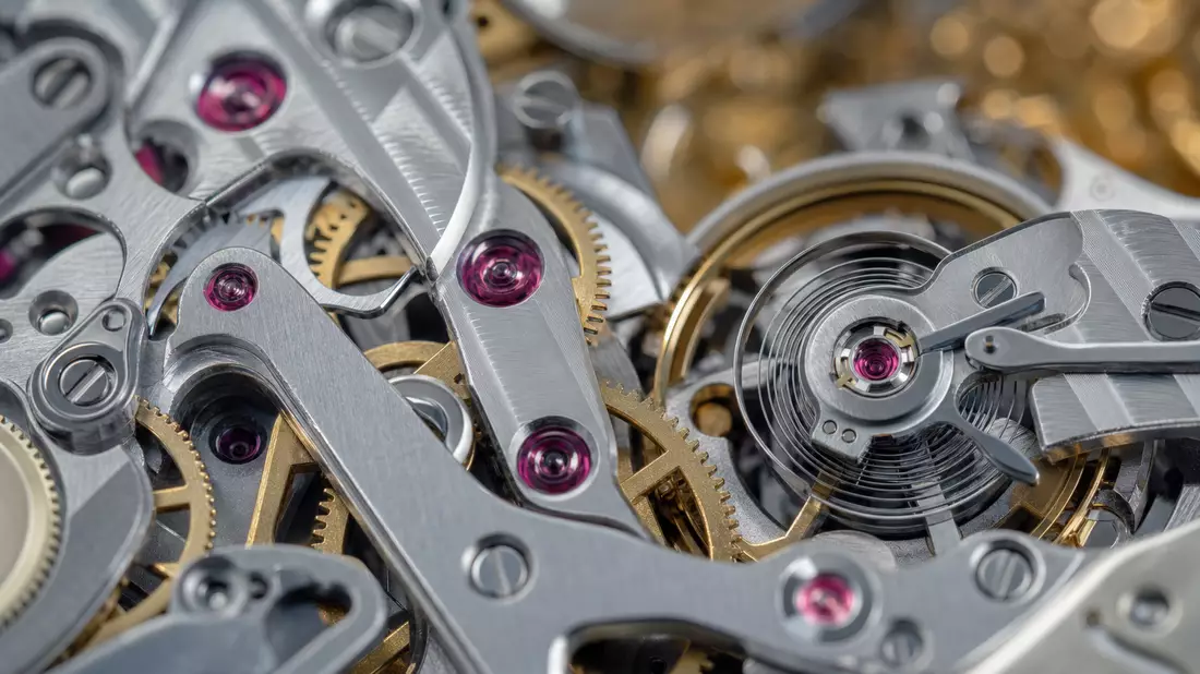 Extremes Makro: poliertes mechanisches Uhrwerk, rote Rubinlager, goldene Zahnräder