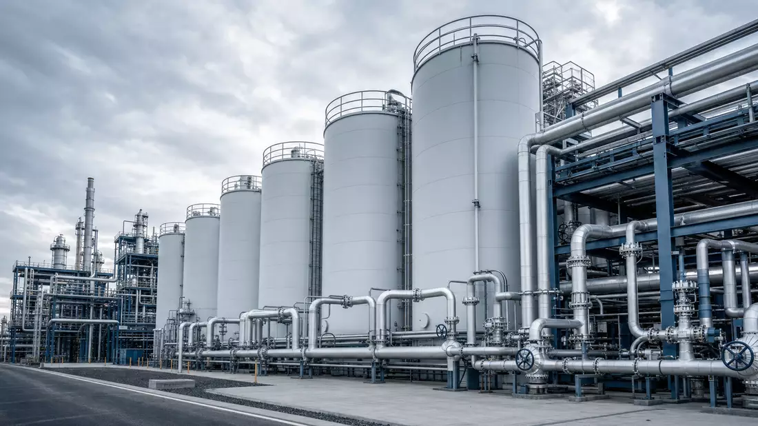 Modern specialty chemical production facility with cylindrical storage tanks and complex silver industrial pipe network