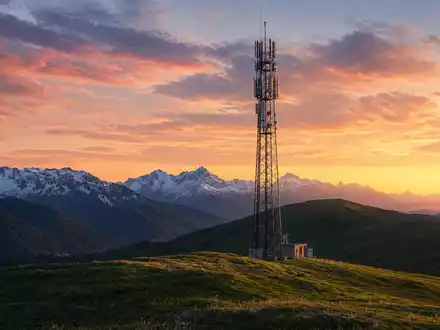 Swisscom AG (CH0008742519) – Mobilfunkmast in Schweizer Alpenlandschaft bei goldenem Sonnenuntergang über schroffen Bergspitzen - Foto: THN