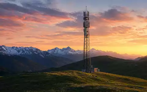 Swisscom AG (CH0008742519) – Mobilfunkmast in Schweizer Alpenlandschaft bei goldenem Sonnenuntergang über schroffen Bergspitzen - Foto: THN