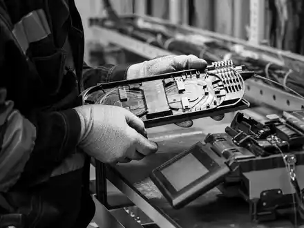 Swisscom AG (CH0008742519) – Glasfaser-Techniker bei dokumentarischer Spleiss-Arbeit als schwarz-weiß Reportagefoto im Berner Schacht. - Foto: THN