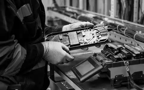 Swisscom AG (CH0008742519) – Glasfaser-Techniker bei dokumentarischer Spleiss-Arbeit als schwarz-weiß Reportagefoto im Berner Schacht. - Foto: THN