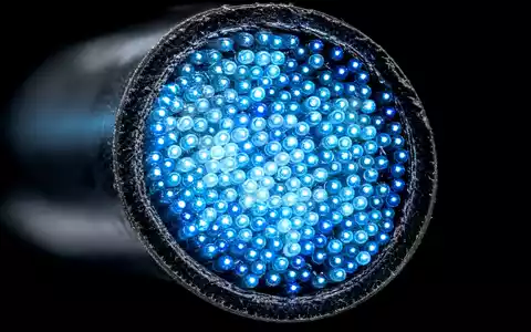 Swisscom AG (CH0008742519) – Makroaufnahme eines Glasfaser-Kabel-Querschnitts mit leuchtenden blauen Lichtleitern in extremer Nähe. - Foto: THN