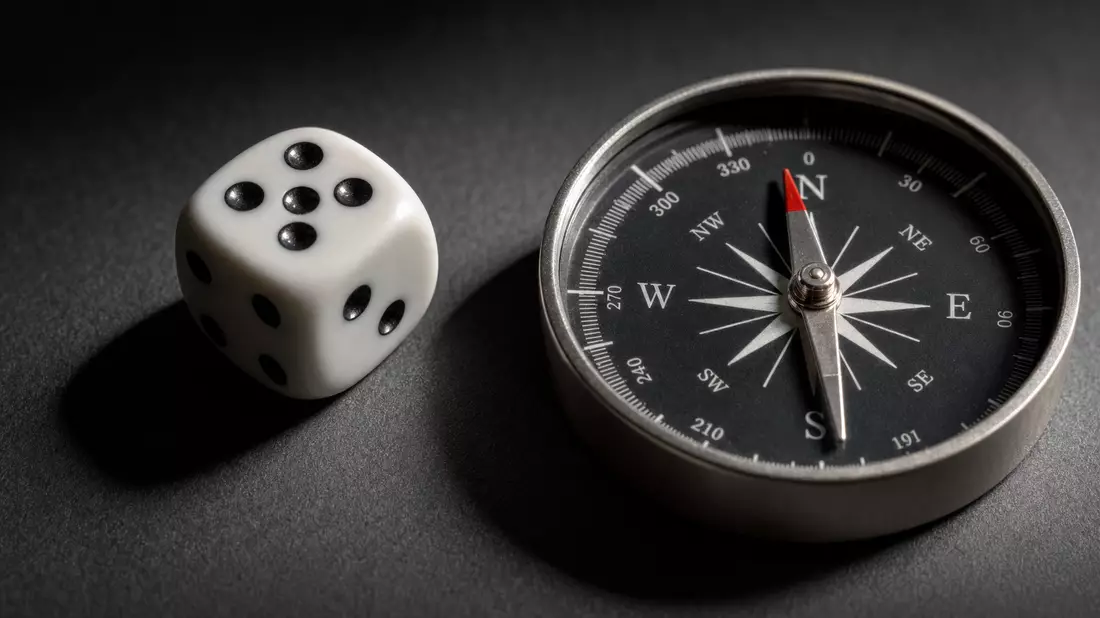 Extreme macro photograph of a white die and a polished compass resting on a dark matte surface. A single directional light source casts sharp dramatic shadows. Shallow depth of field keeps both objects in razor-sharp focus against a neutral grey-black bac