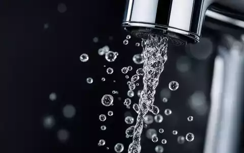 Geberit (CH0030170408) Makro-Detail zeigt einen Wasserstrahl und Tropfen an der glänzenden Chrom-Armatur - Foto: THN