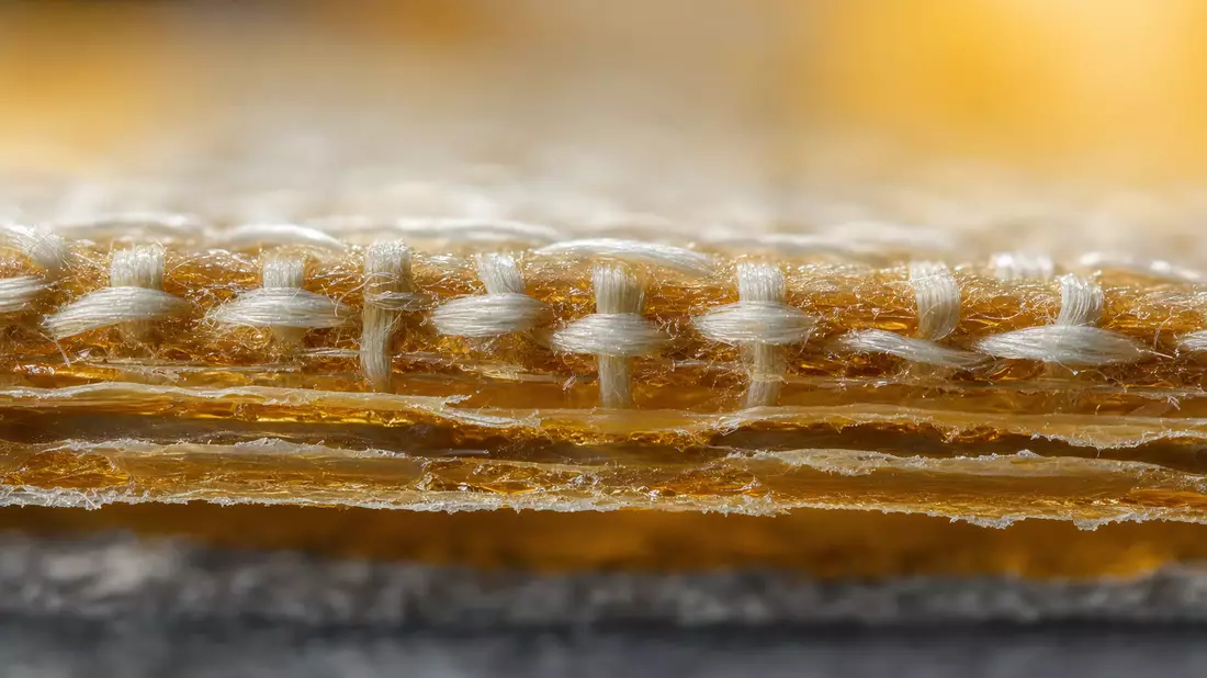 Extreme macro photography close-up of an adhesive tape cross-section showing detailed fiber weave st