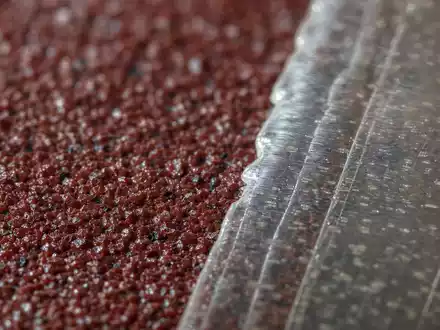 Makroaufnahme von Schleifpapierkörnern und Klebefolie veranschaulicht Materialien von 3M Company, ISIN US88579Y1010, Industriesparte - Foto: THN
