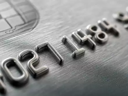 Makroaufnahme geprägter Ziffern auf grauer Kreditkarte, American Express Co. (US0258161092), Kreditkartenbranche Materialdetail in Nahaufnahme - Foto: THN