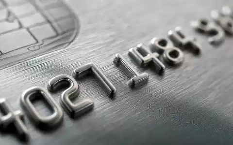 Makroaufnahme geprägter Ziffern auf grauer Kreditkarte, American Express Co. (US0258161092), Kreditkartenbranche Materialdetail in Nahaufnahme - Foto: THN