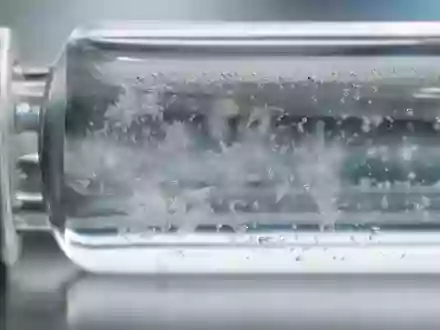 Amgen Inc. (ISIN US0311621009) veranschaulicht diese Makroaufnahme einer gefrorenen Wirkstofflösung im Glasfläschchen - Foto: THN