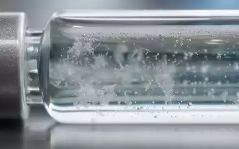 Amgen Inc. (ISIN US0311621009) veranschaulicht diese Makroaufnahme einer gefrorenen Wirkstofflösung im Glasfläschchen - Foto: THN