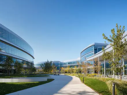 Fotorealistisches Bild zeigt moderne Unternehmenszentrale von Apple Inc., ISIN US0378331005, mit Glasfassade und Technologie-Campus - Foto: THN