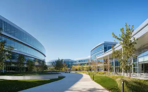 Fotorealistisches Bild zeigt moderne Unternehmenszentrale von Apple Inc., ISIN US0378331005, mit Glasfassade und Technologie-Campus - Foto: THN