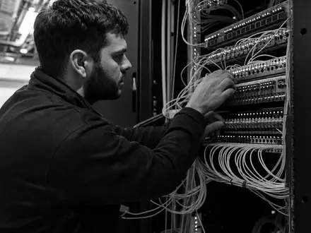 Dokumentarische Schwarzweiß-Aufnahme eines Netzwerktechnikers repräsentiert Cisco Systems Inc., ISIN US17275R1023, im IT-Infrastruktursektor - Foto: THN
