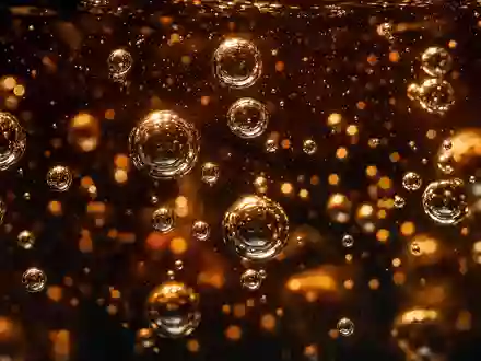 Coca-Cola US1912161007 zeigt dramatische Makro-Nahaufnahme von aufsteigenden Sprudelbläschen in leuchtend goldbrauner Cola - Foto: THN