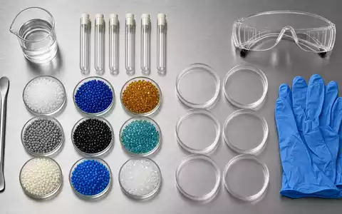 Dow Inc. US2605571031 Chemie Flatlay mit Granulat Proben, Reagenzgläsern, Handschuhen und Schutzbrille auf Stahl - Foto: THN