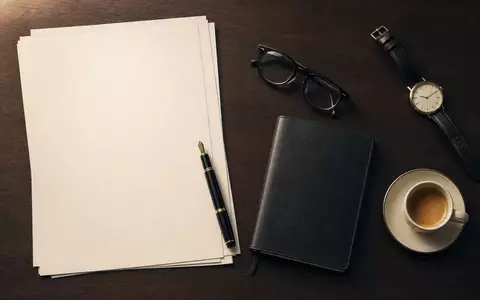 Goldman Sachs US38141G1040 Banker Flatlay mit Füller Brille Uhr Notizbuch und Kaffee auf Mahagoni - Foto: THN