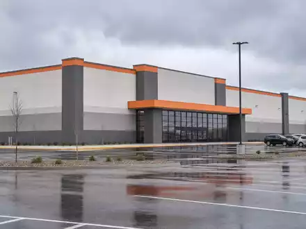 Home Depot US4370761029 als großes Big-Box-Lagergebäude mit dezenten orangefarbenen Fassaden-Akzenten und Parkplatz - Foto: THN