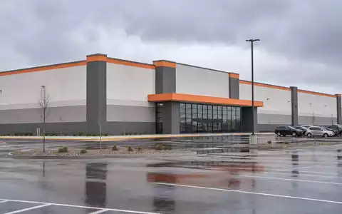 Home Depot US4370761029 als großes Big-Box-Lagergebäude mit dezenten orangefarbenen Fassaden-Akzenten und Parkplatz - Foto: THN