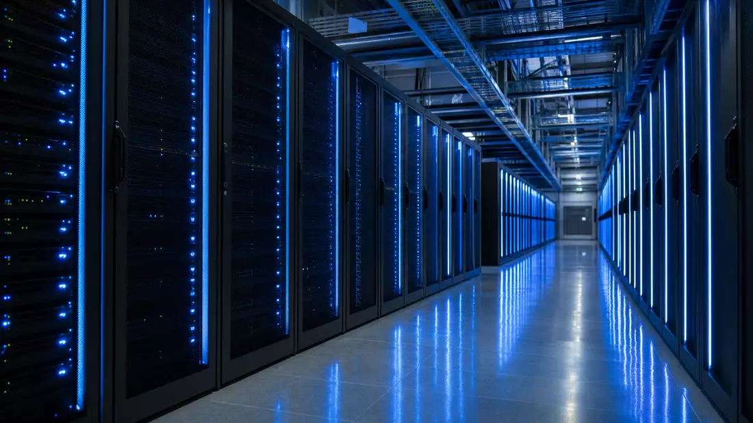 Photorealistic view down a long enterprise mainframe data center corridor, tall black server cabinets lined with glowing blue LED strips on both sides, cool blue ambient light reflecting off the polished floor, deep perspective showing the aisle vanishing