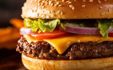 McDonald's Burger-Nahaufnahme US5801351017 zeigt schmelzenden Käse, frischen Salat und Sesam im Licht - Foto: THN