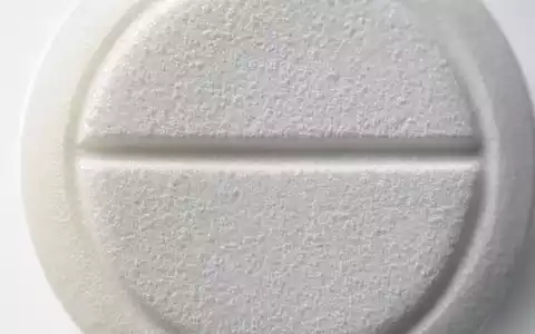 Merck US58933Y1055 Tabletten-Makro: Weiße Tablette mit Bruchrille und Tablettenpresse-Spur im extremen Nahaufnahme-Zoom. - Foto: THN