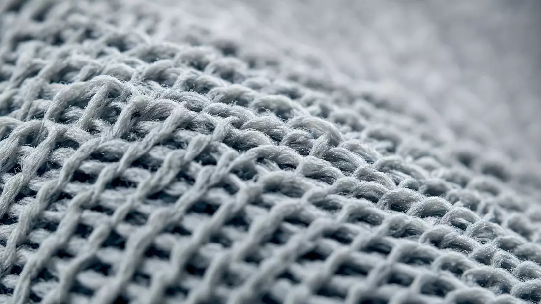 Makro-Nahaufnahme des feinen Strickgewebes eines neutralen Sportschuhs in Grautönen