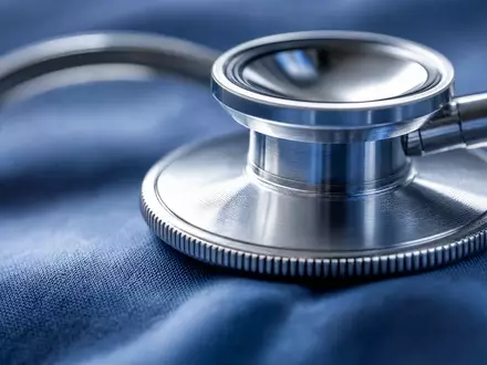 UnitedHealth Group US91324P1021 visualisiert durch extreme Makroaufnahme eines Stethoskops auf blauem Stoff - Foto: THN