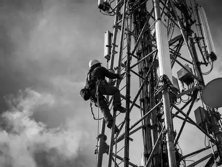 Verizon US92343V1044 – Schwarzweiß-Reportage eines Technikers beim sicheren Klettern an einem hohen Mobilfunkturm - Foto: THN