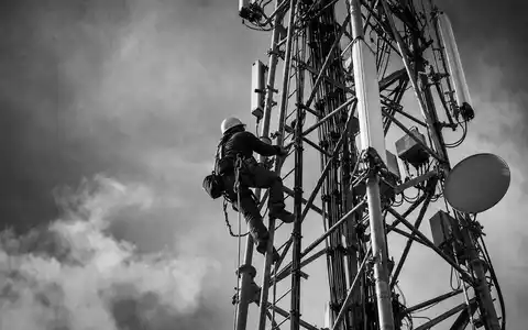 Verizon US92343V1044 – Schwarzweiß-Reportage eines Technikers beim sicheren Klettern an einem hohen Mobilfunkturm - Foto: THN