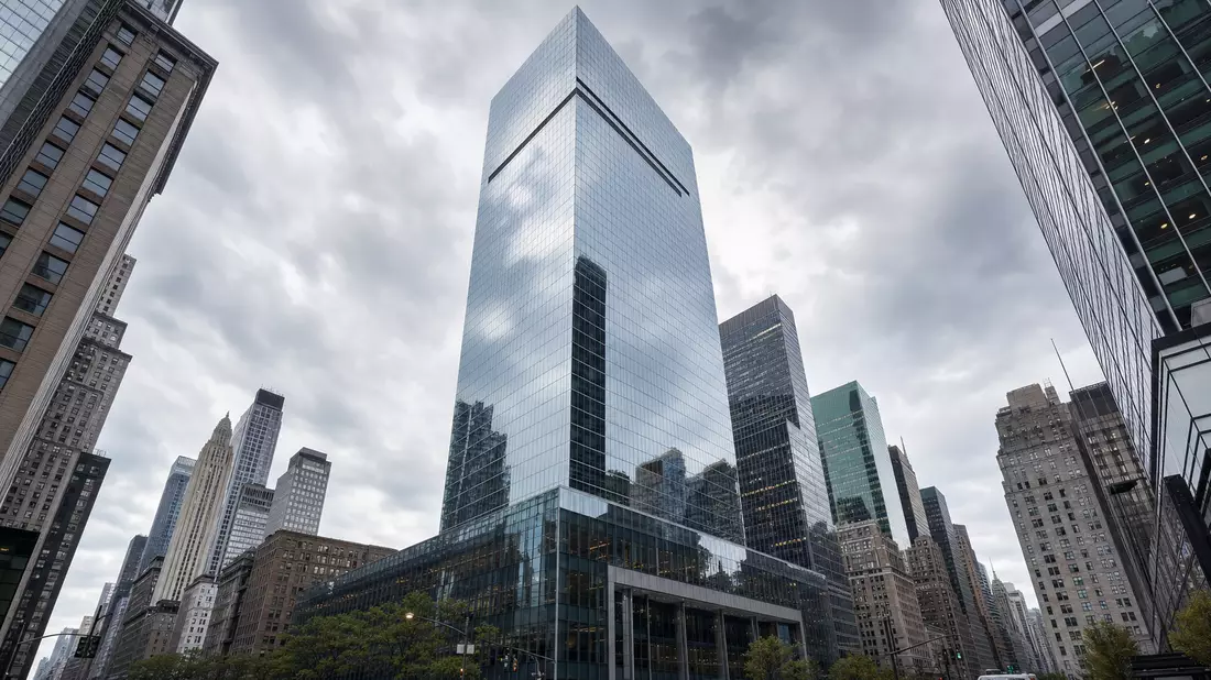 Architekturfotografie eines markenneutralen Glas-Wolkenkratzers in Midtown Manhattan, Froschperspektive, bewölkter Himmel spiegelt sich in der Fassade