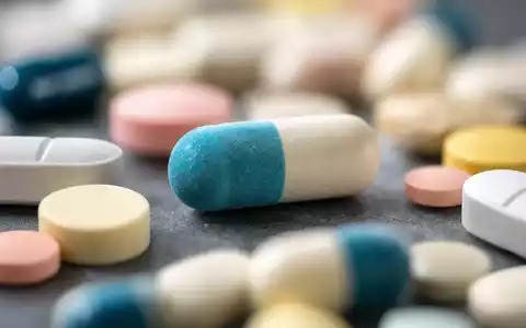 Walgreens US9314271019 zeigt extreme Makro-Nahaufnahme farbiger pharmazeutischer Tabletten und Kapseln auf grauem Untergrund - Foto: THN