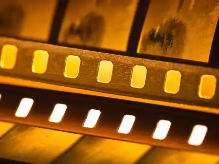 Disney US9314271084 im extremen Makroblick auf goldenen 35mm-Filmstreifen mit klar beleuchteten einzelnen Perforationslöchern - Foto: THN