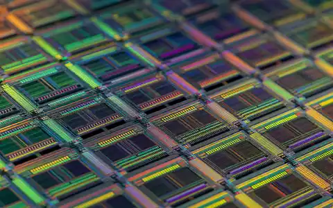 Broadcom Inc. (US11135F1012): detailreiche Makroaufnahme eines Halbleiter-Wafers zeigt feinste, schimmernde Mikrochip-Schaltkreisstrukturen in Nahaufnahme - Foto: THN